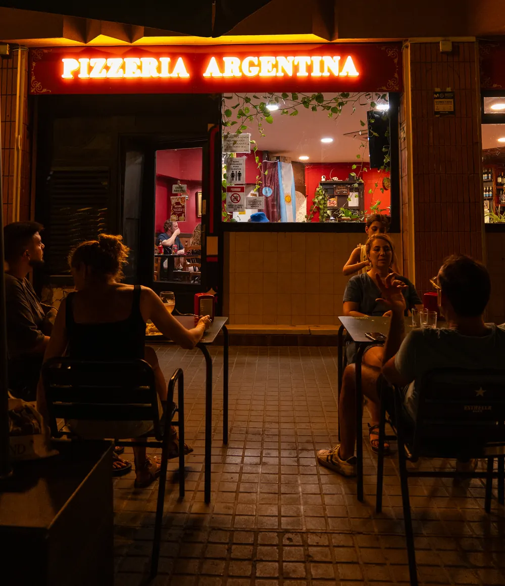 Facciata di Salta Food di notte con l’insegna al neon «Pizzería Argentina»