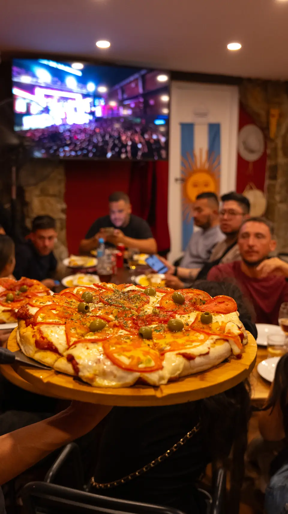 Grupo mirando un partido de Argentina con pizzas en la mesa